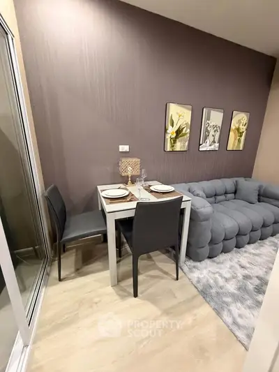 Modern living room with stylish gray sofa and dining area, featuring elegant decor and cozy ambiance.