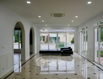 Spacious modern living room with elegant marble flooring and large windows offering garden views.
