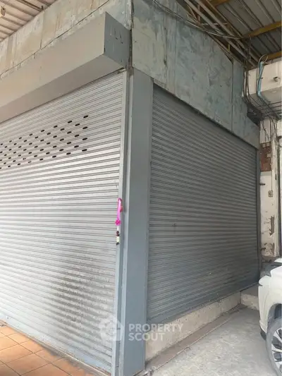 Commercial property with closed metal shutters and adjacent parking space.