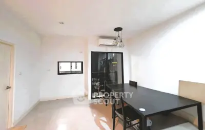 Modern dining area with sleek black table and chairs, featuring a stylish pendant light and air conditioning.