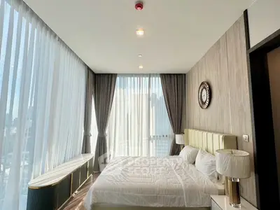Luxurious bedroom with floor-to-ceiling windows and elegant decor in modern apartment.