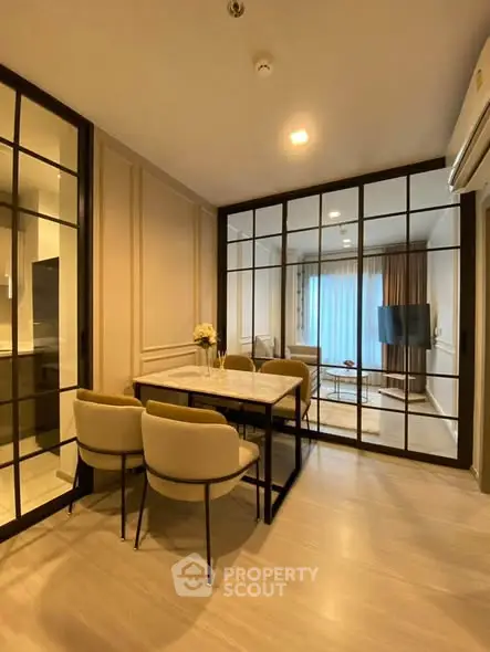 Modern dining area with glass partition and cozy seating in a stylish apartment.