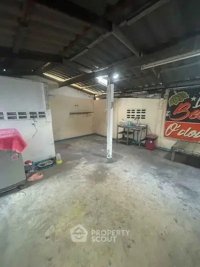 Spacious industrial-style room with exposed beams and concrete floor, ideal for creative projects.