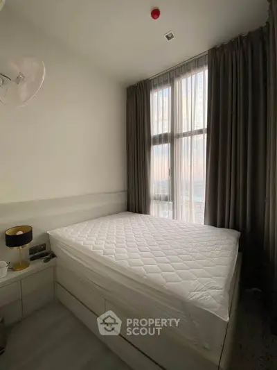Cozy bedroom with large window and modern furnishings, perfect for relaxation and comfort.