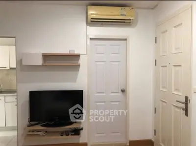 Modern apartment interior with TV, air conditioning, and kitchen view.