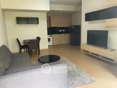 Spacious living room with modern furniture and open kitchen layout, perfect for comfortable living.