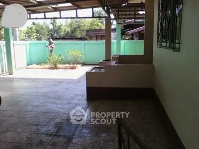 Spacious outdoor area with tiled flooring and garden view, perfect for relaxation and gatherings.