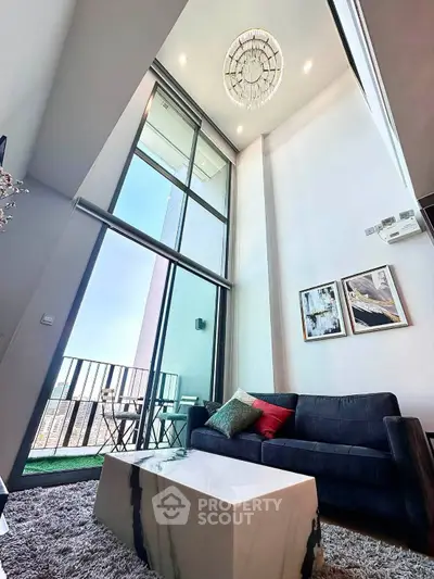 Luxurious high-ceiling living room with modern decor and balcony view