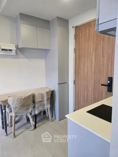 Modern compact kitchen with sleek cabinetry and dining area in a stylish apartment.