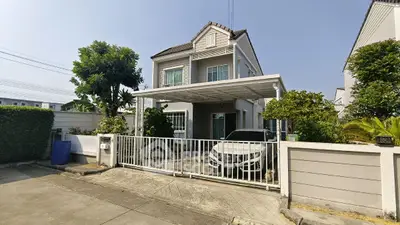 Charming two-story house with carport and lush garden in a serene neighborhood.