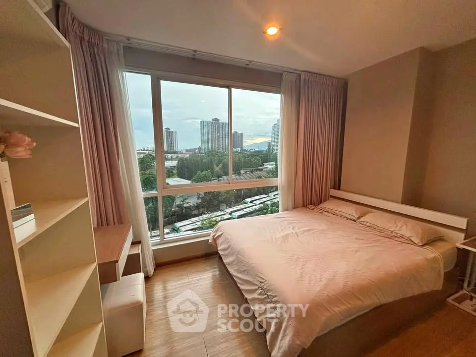 Cozy bedroom with large window offering stunning city view, perfect for urban living.