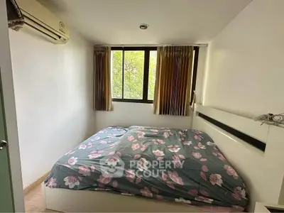 Cozy bedroom with floral bedding and large window offering natural light
