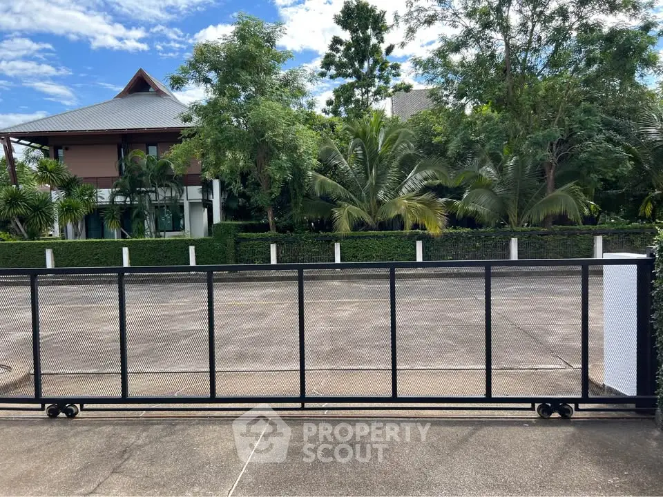 Spacious driveway with modern gate and lush greenery in a serene residential area.
