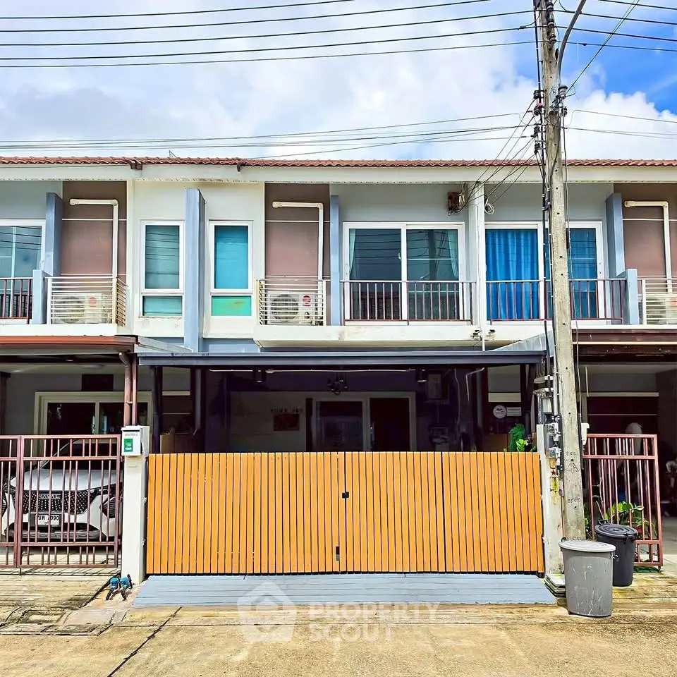 Modern townhouse exterior with gated entrance and parking space in a suburban neighborhood.