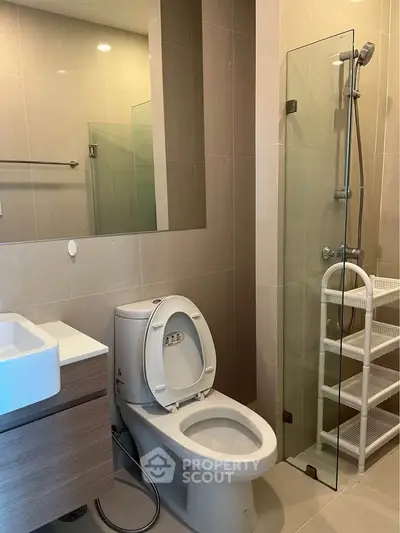 Modern bathroom with glass shower and sleek fixtures in contemporary apartment.