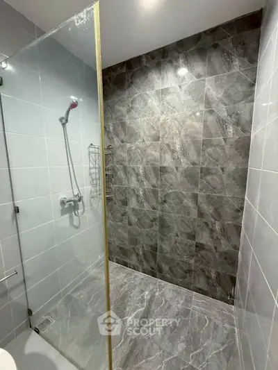 Modern bathroom with sleek glass shower and elegant gray tiles