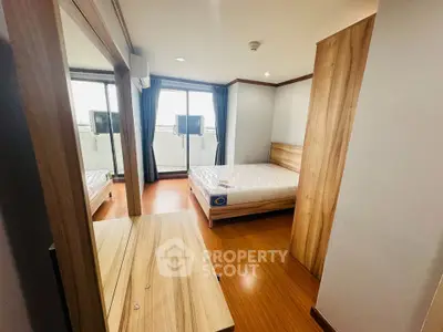 Spacious bedroom with wooden flooring and large windows offering natural light.