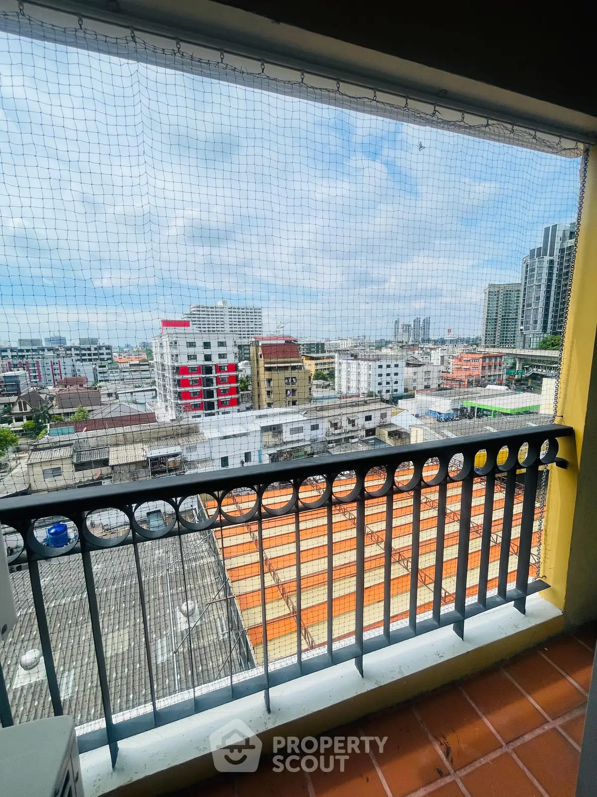Stunning cityscape view from a high-rise balcony with protective netting, perfect for urban living.