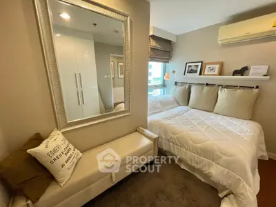 Cozy bedroom with modern decor and ample natural light, featuring a comfortable bed and stylish mirror.