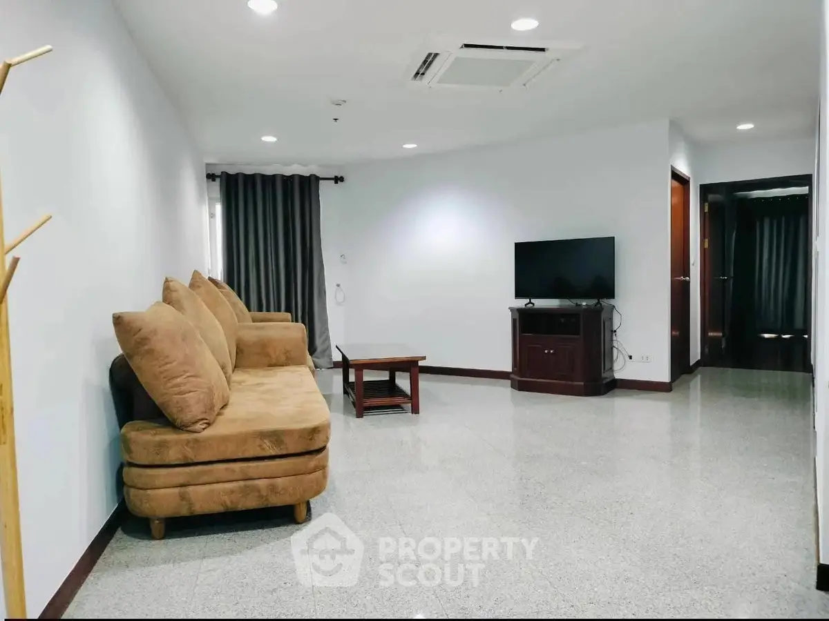 Spacious living room with cozy sofa and modern TV setup in a stylish apartment.