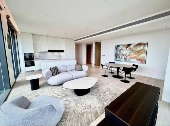Luxurious modern living room with open kitchen, stylish furniture, and large windows offering natural light.