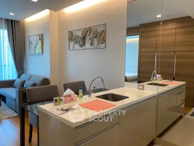 Modern open-layout kitchen and living room with sleek design and mirrored accents.