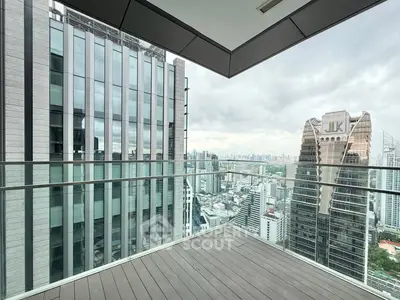 Stunning cityscape view from a modern balcony with glass railing in a high-rise building.