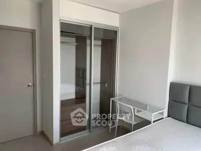 Modern bedroom with sleek glass wardrobe and minimalist desk setup.