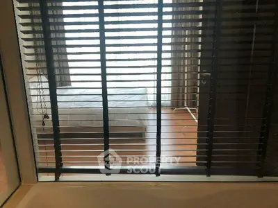 Cozy bedroom with large window and blinds offering natural light and privacy.