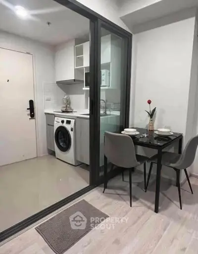 Modern compact kitchen with washing machine and dining area in stylish apartment.