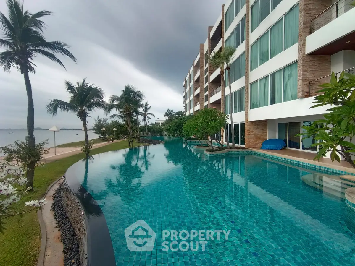 Luxurious beachfront condominium with stunning pool and palm trees, perfect for tropical living.