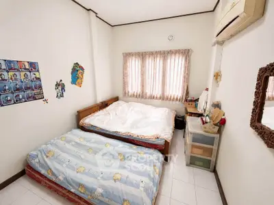 Cozy bedroom with two beds, air conditioning, and natural light through curtains.