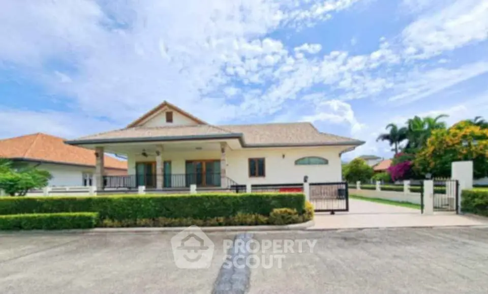 Charming suburban house with lush garden and spacious driveway under a clear blue sky.