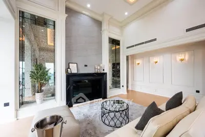 Luxurious living room with elegant decor and high ceilings, featuring a modern fireplace and plush seating.