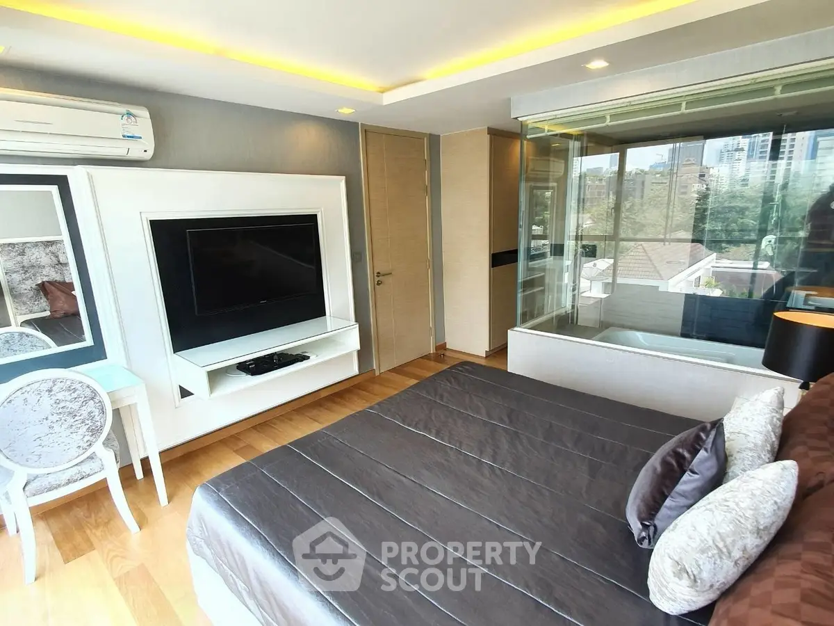 Luxurious bedroom with modern decor and large window offering stunning city views.