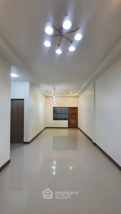 Spacious empty living room with modern lighting and glossy tile flooring.