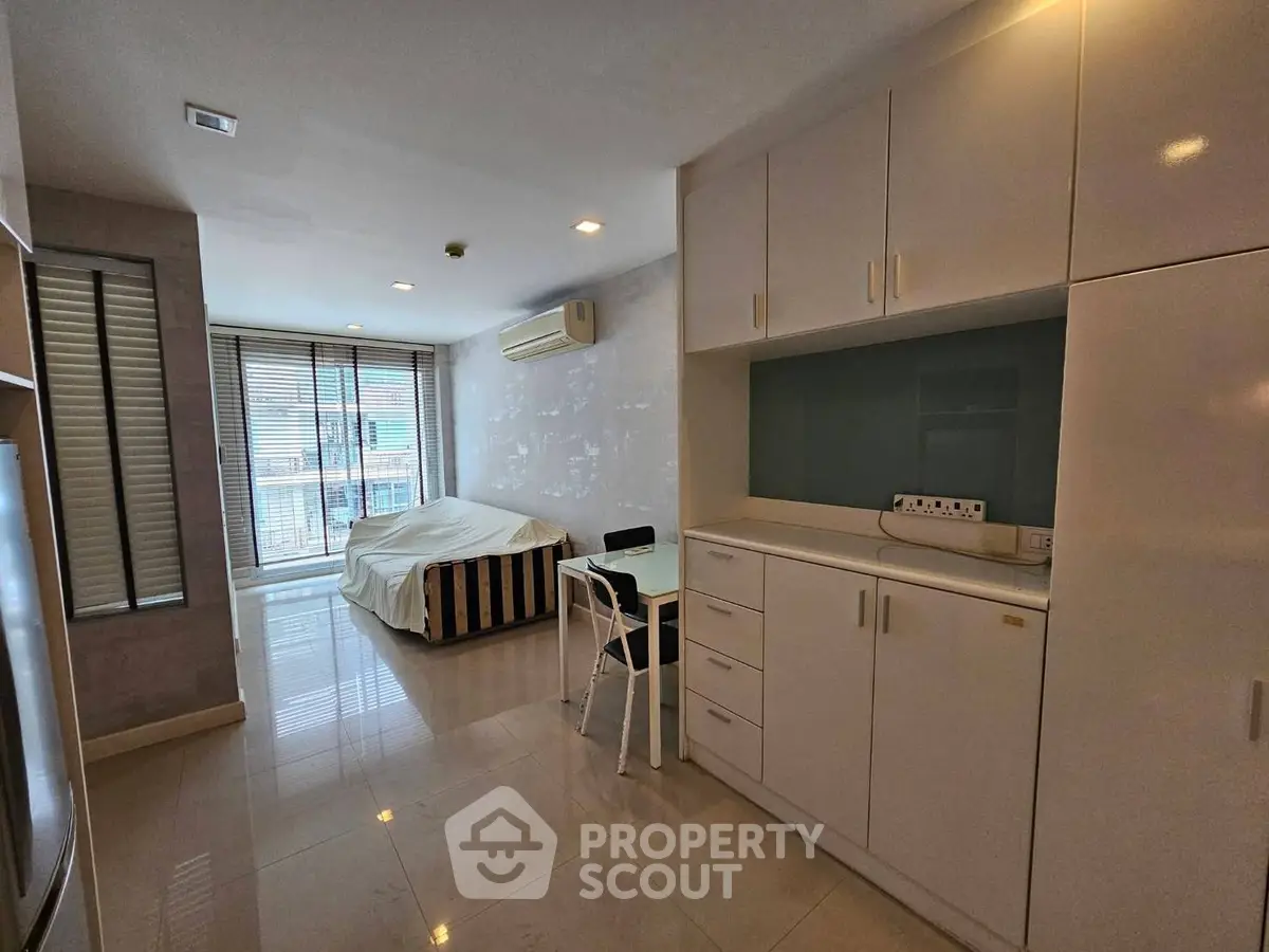 Modern studio apartment with sleek cabinetry and large windows offering ample natural light.