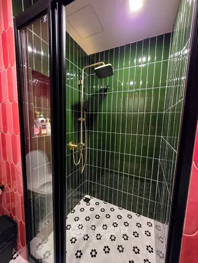 Stylish modern bathroom with black and green tiles and elegant shower fixtures.
