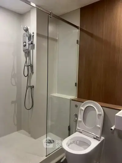 Modern bathroom with glass shower and sleek wooden accents, perfect for contemporary living.