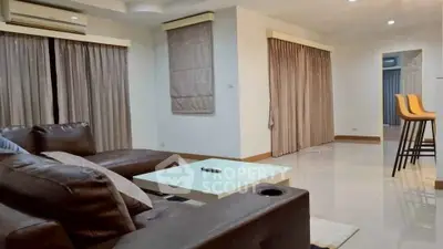 Spacious modern living room with leather sofa and stylish bar stools, perfect for relaxation and entertainment.