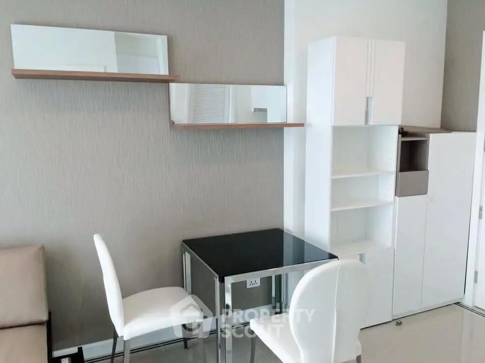 Modern minimalist dining area with sleek white furniture and wall-mounted shelves.