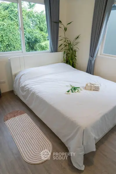 Cozy bedroom with large windows and lush greenery view, featuring a modern bed and elegant decor.