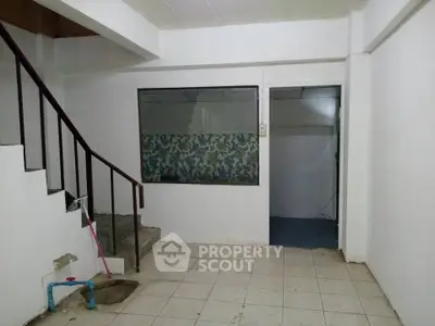 Spacious interior with tiled floor and staircase, ideal for renovation.