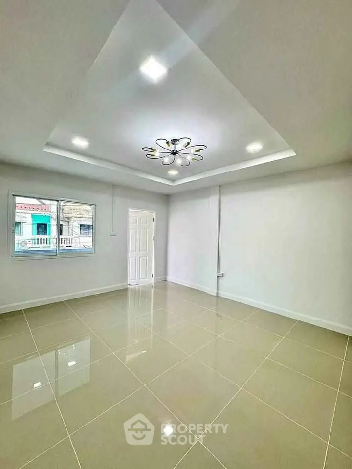 Spacious empty room with modern ceiling light and large window