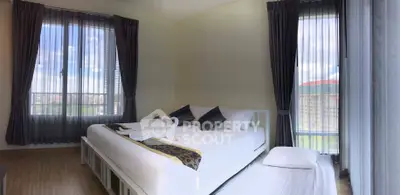 Spacious bedroom with large windows and elegant decor, offering a serene and inviting atmosphere.