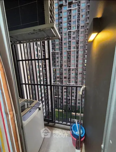 Compact balcony with washing machine and city view in high-rise apartment.