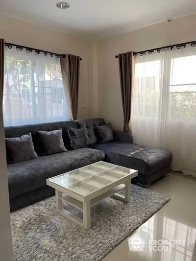 Cozy living room with modern gray sectional sofa and glass coffee table