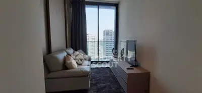 Modern living room with city view, featuring cozy sofa and sleek TV setup.