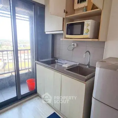 Compact kitchen with balcony access and modern appliances in urban apartment