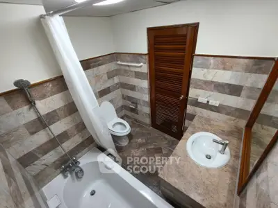 Spacious bathroom with elegant marble tiles and modern fixtures in a stylish real estate property.